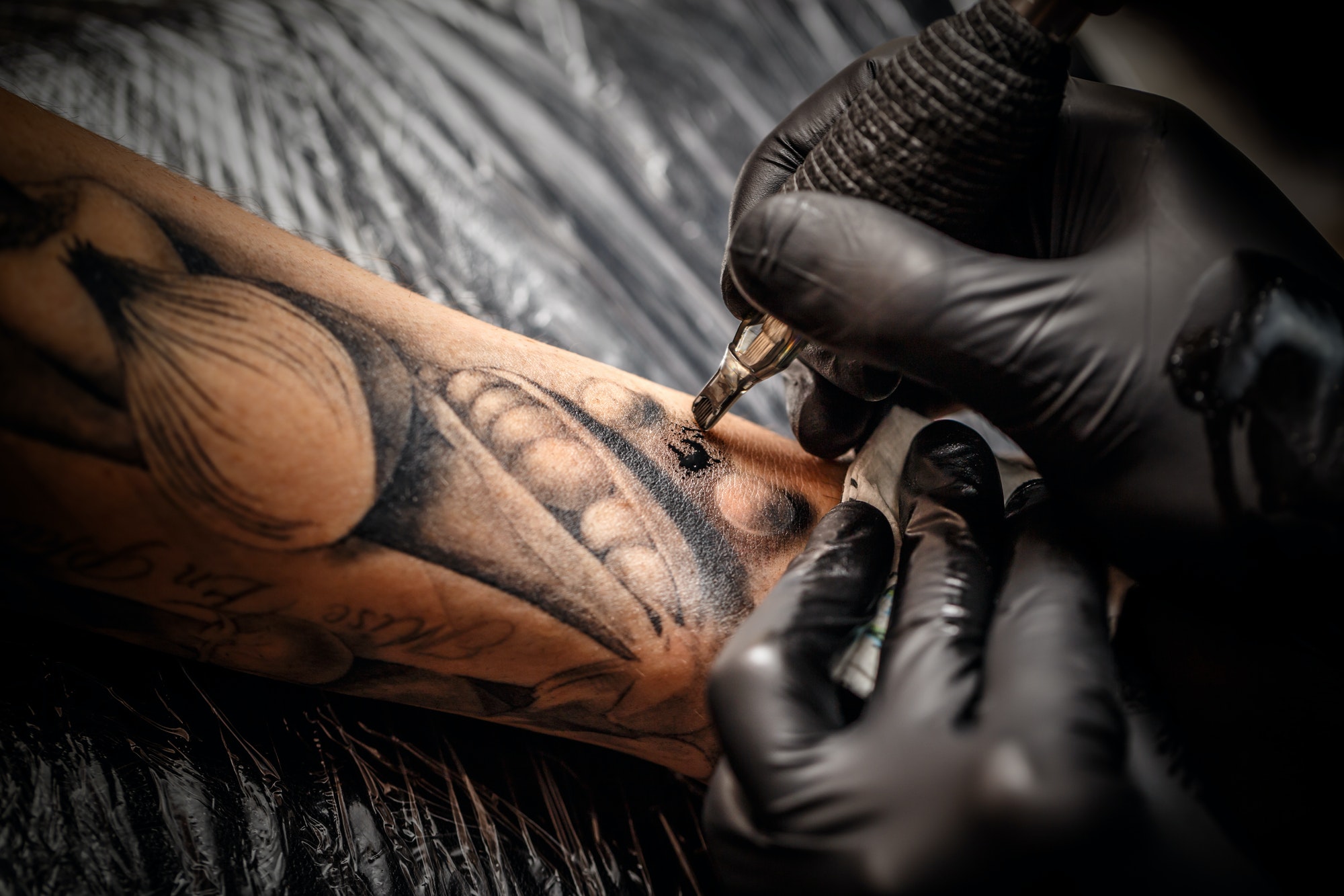 Tattoo artist inking detailed black work on forearm